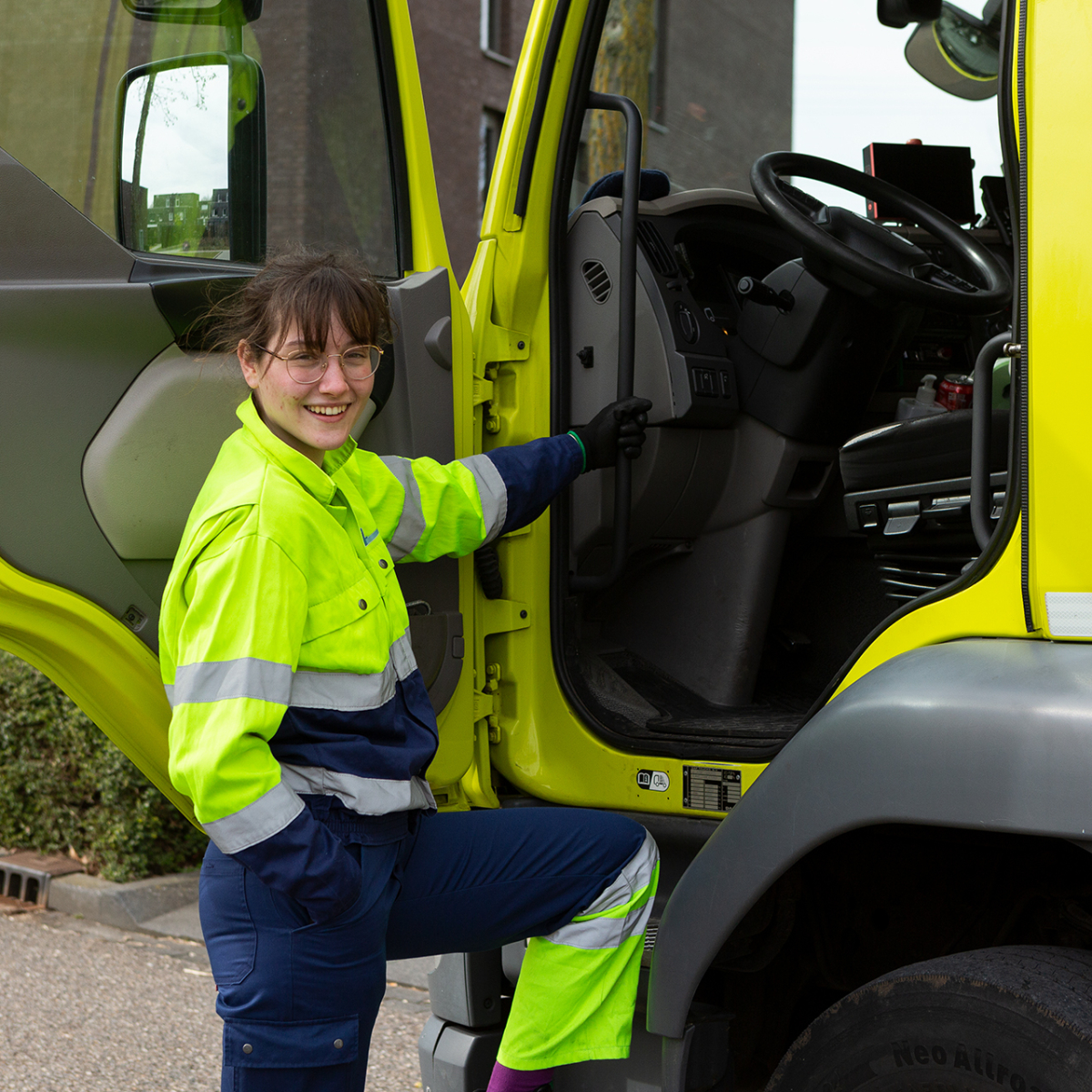 Een lachende inzamelmedewerkster staat bij een wagen van Rd4.
